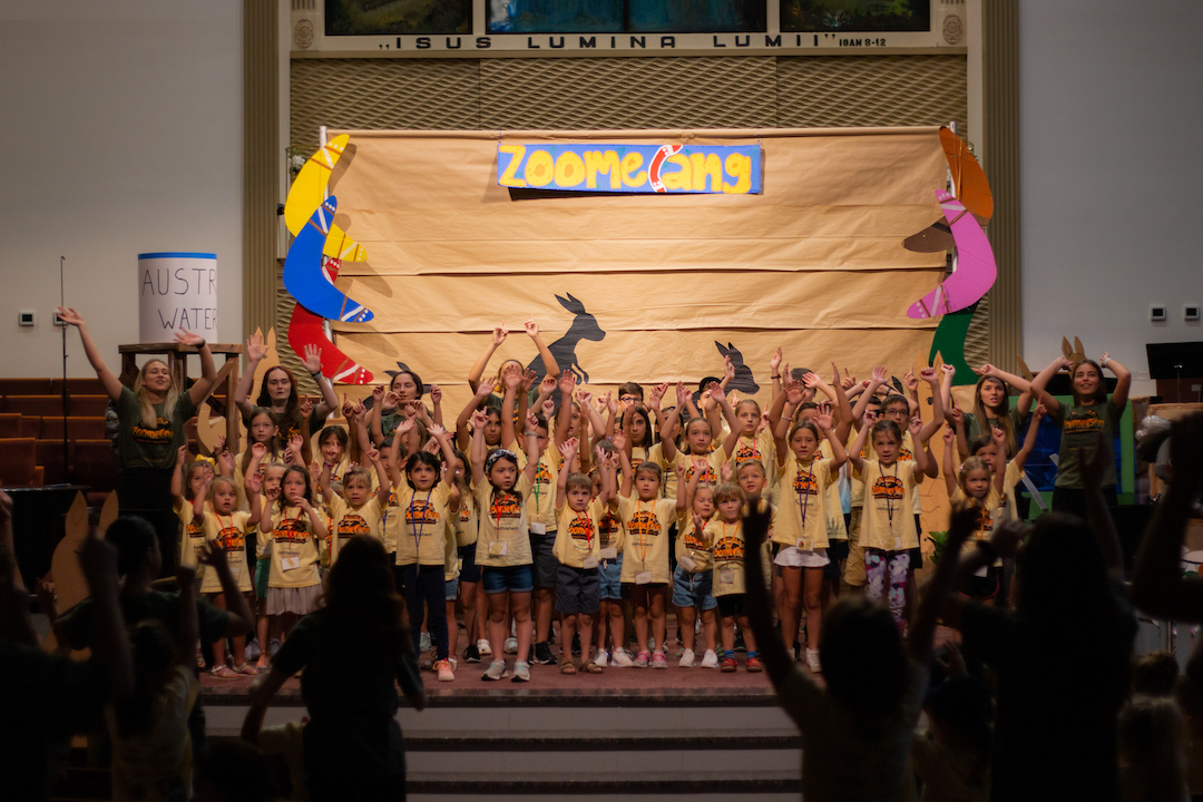 Children raising their hands during a Sunday School program